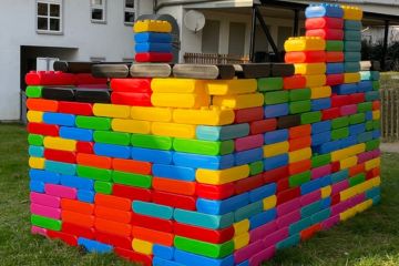 Bausteine XXL-Blocks als Haus aufgebaut. Es steht auf einer Wiese vor einem Haus.