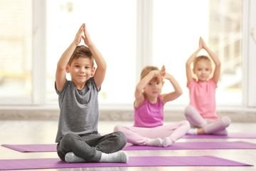 3700 Kinderyoga 3bis5 Jahre Man sieht drei fröhliche Kleinkinder in einer Yoga-Pose auf einer Matte.